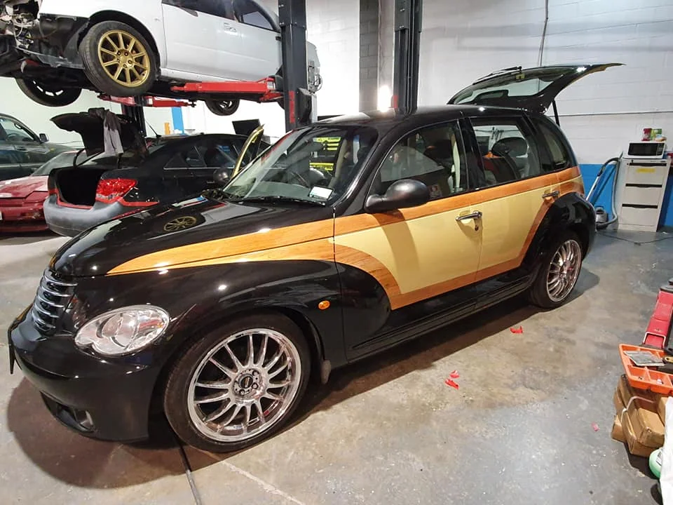 Black hatchback with custom two-tone woodgrain paintwork in the workshop